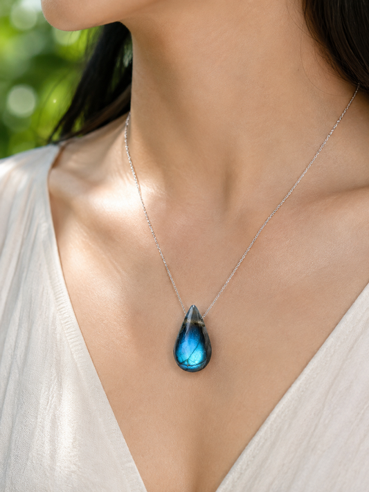 Blue-flash teardrop pendant worn at the chest on a fine silver-colored chain