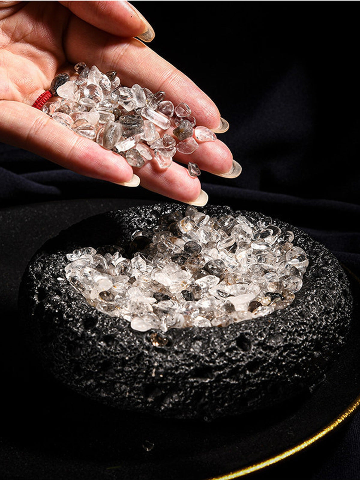 Black cleansing bowl being filled with crystal chips