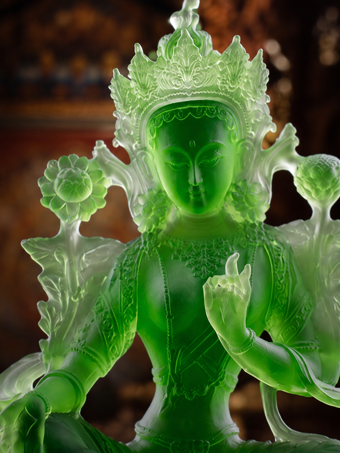Close view of Green Tara in liuli glass, showing the crown, lotus stems, and hand gesture