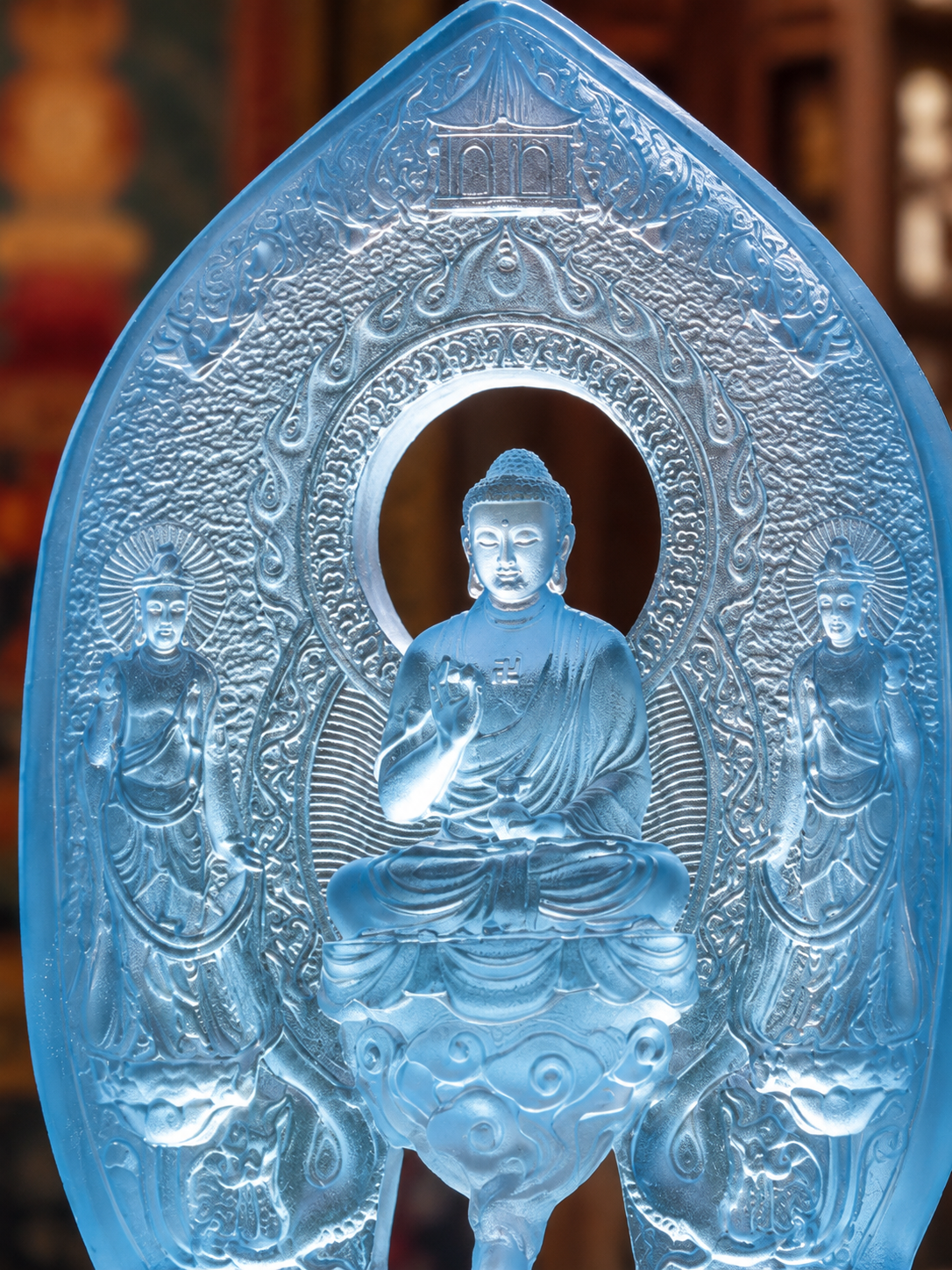 Close view of the plain Medicine Buddha triad, with the seated central figure and two smaller figures in blue glass