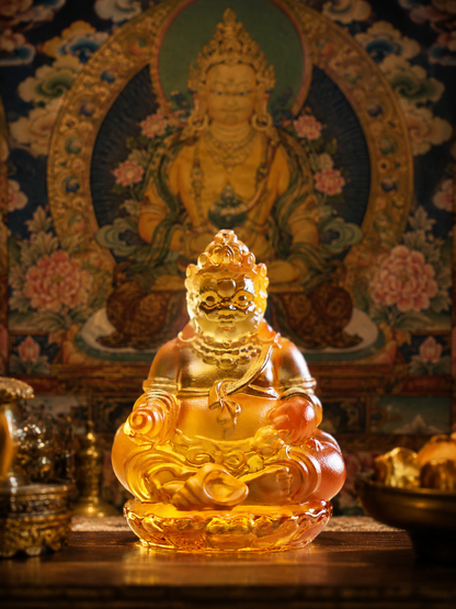 Yellow Jambhala statue before a traditional thangka