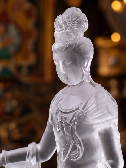 Close view of clear liuli Guanyin, showing the lowered gaze, draped robes, and jewelry