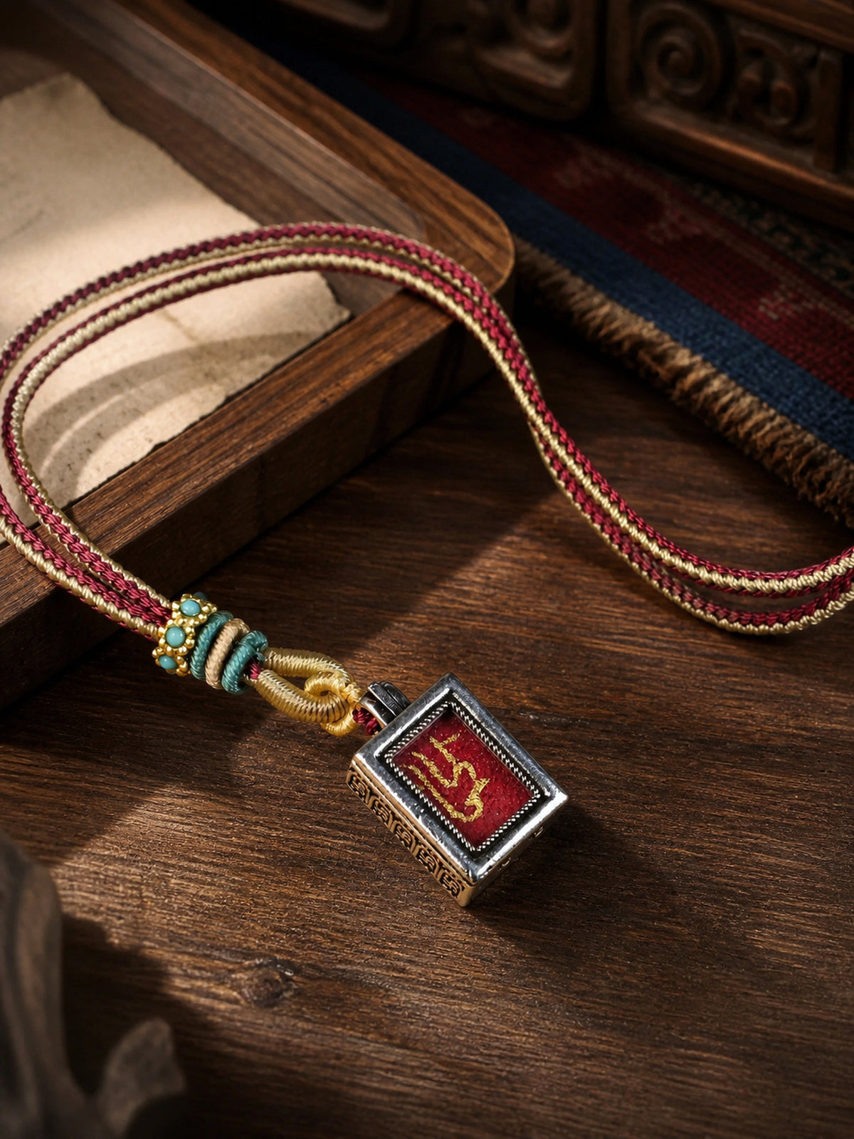 Amitabha Buddha design mini thangka pendant: painted symbol on red, with a red-and-cream braided cord