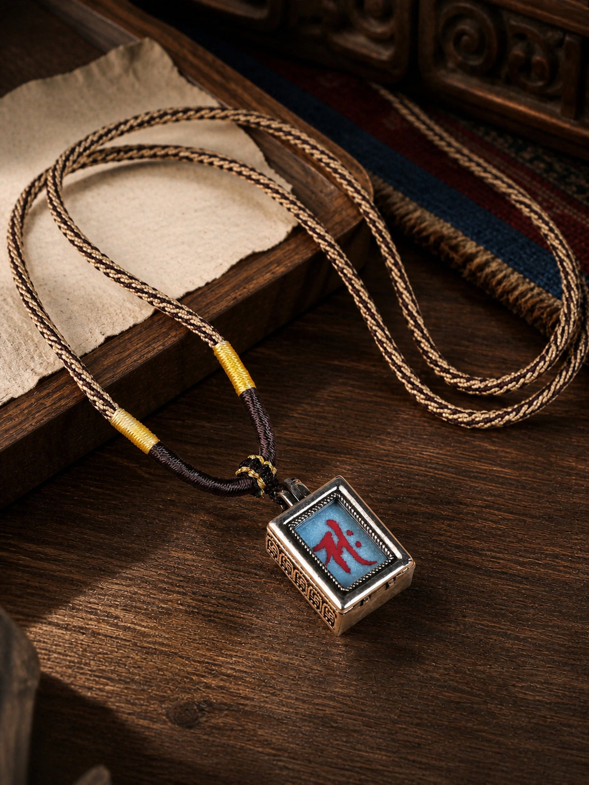 Mahasthamaprapta Bodhisattva design mini thangka pendant: painted symbol on pale blue, with a brown-and-cream braided cord