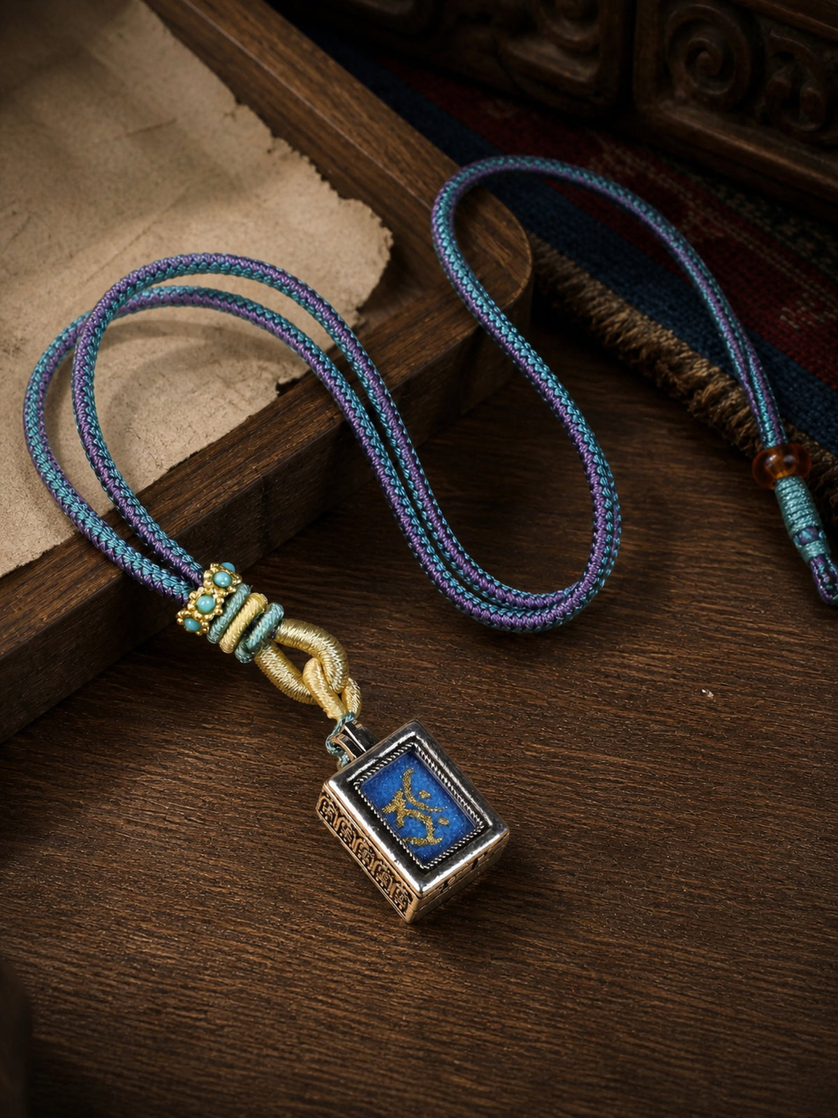 Akasagarbha Bodhisattva design mini thangka pendant: painted symbol on blue, with a blue-and-purple braided cord