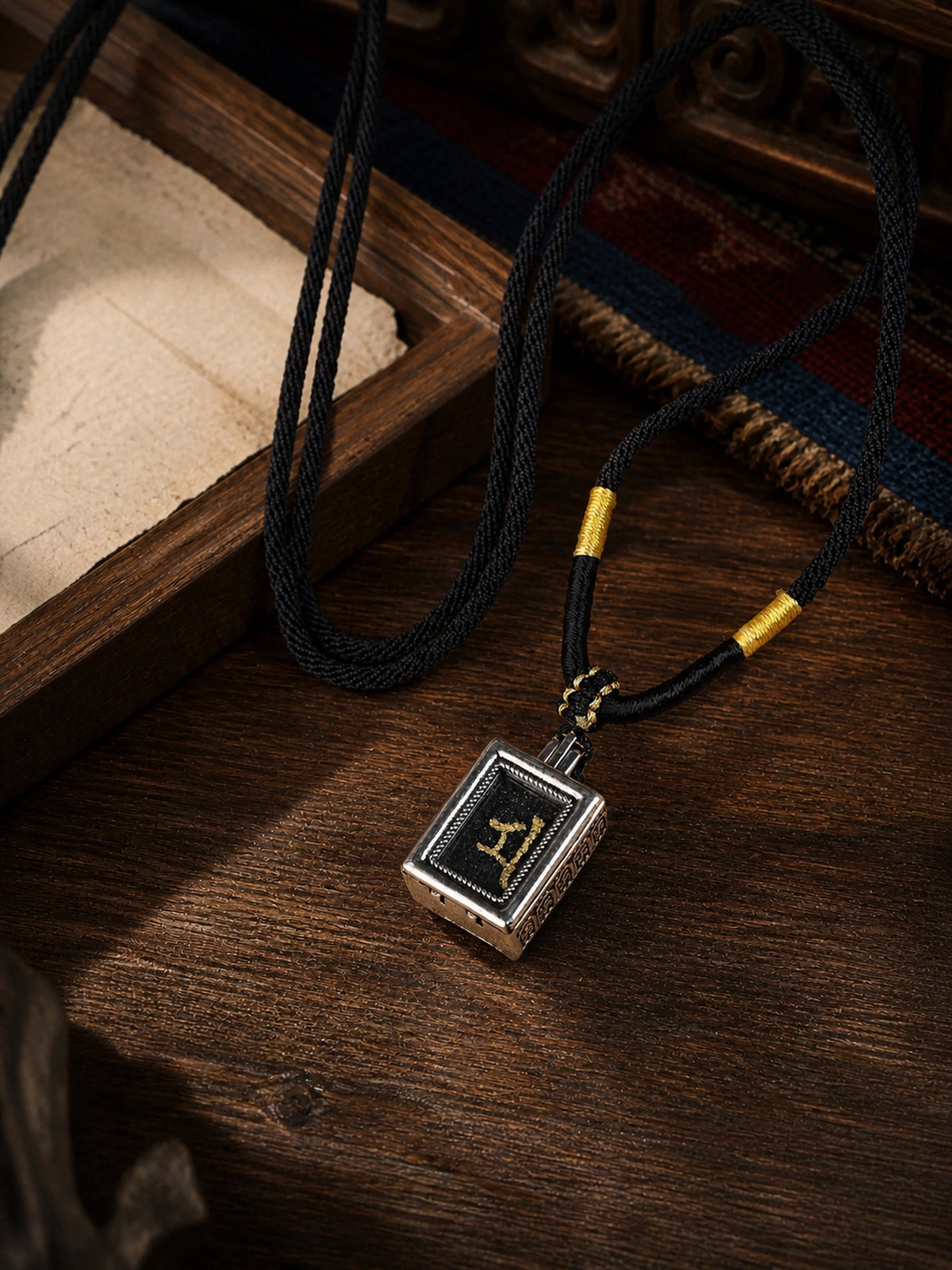 Marici design mini thangka pendant: painted symbol on black, with a black braided cord