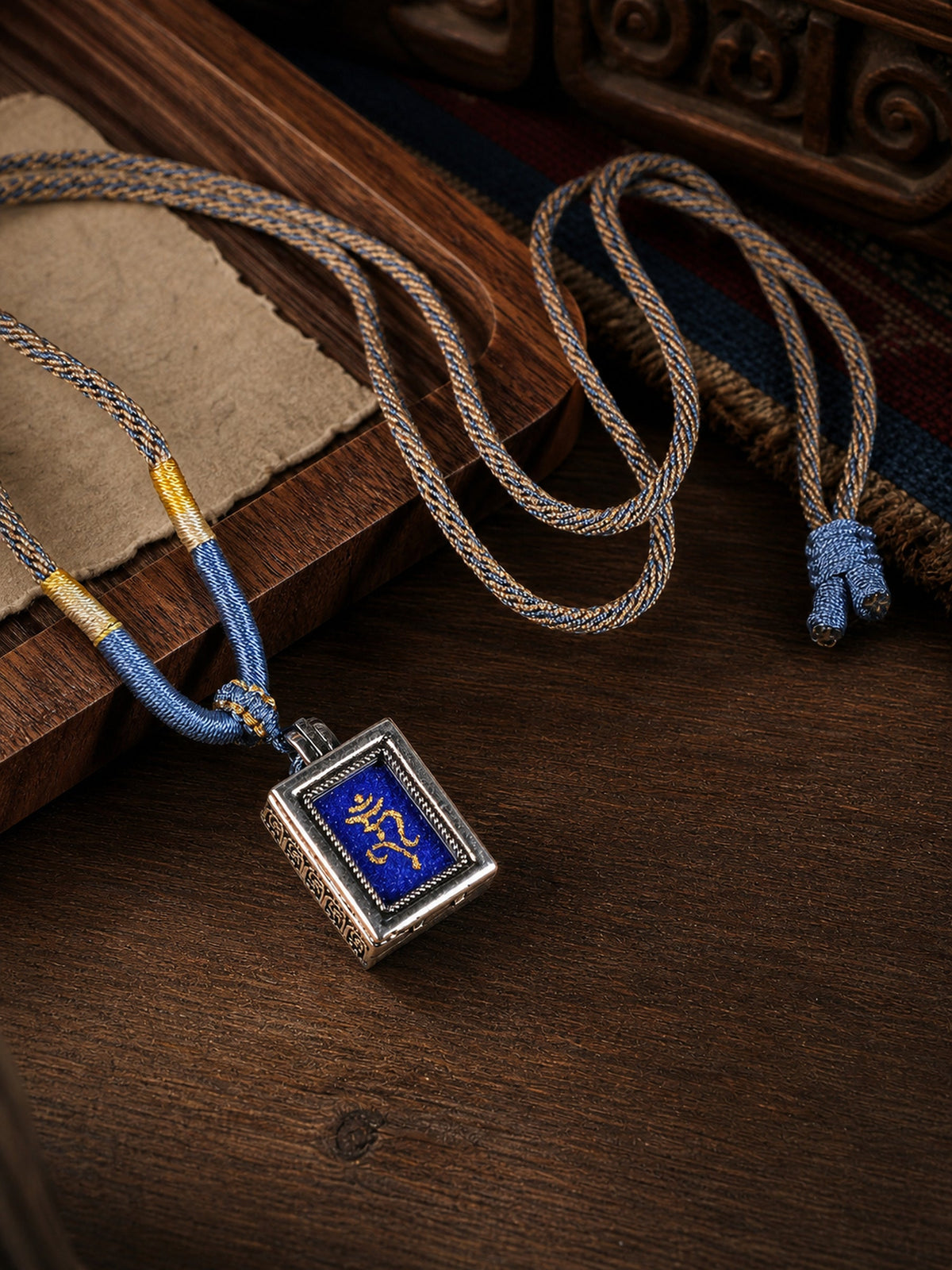 Medicine Buddha design mini thangka pendant: painted symbol on blue, with a blue-and-gray braided cord