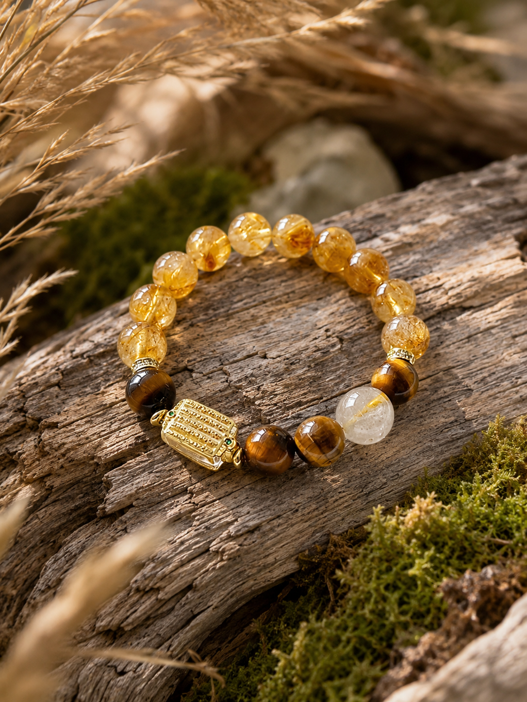 Yellow crystal bracelet arranged on weathered wood beside moss and grasses