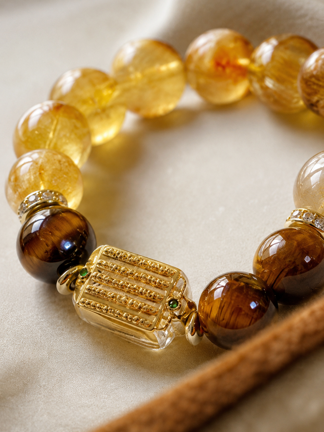 Yellow crystal bracelet with tiger's eye accents and a rectangular gold-colored focal