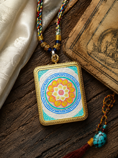 Six-Syllable Mantra pendant and braided necklace laid on wood beside printed pages