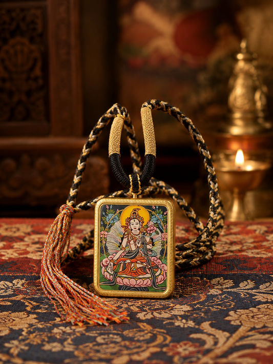 White Tara thangka pendant displayed with a black-and-gold cord and rust-colored tassel