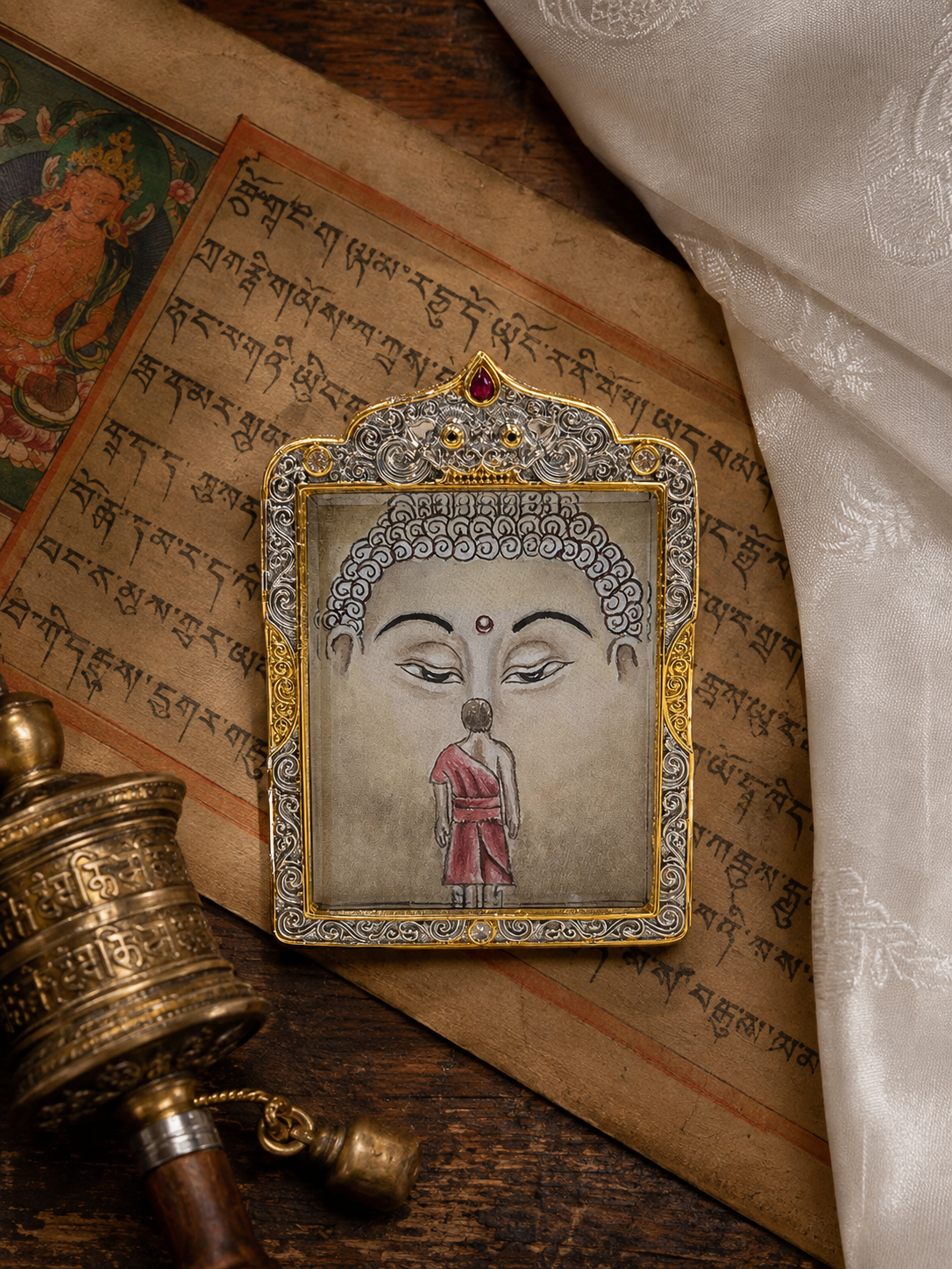 Shakyamuni pendant lying on printed pages beside cream fabric