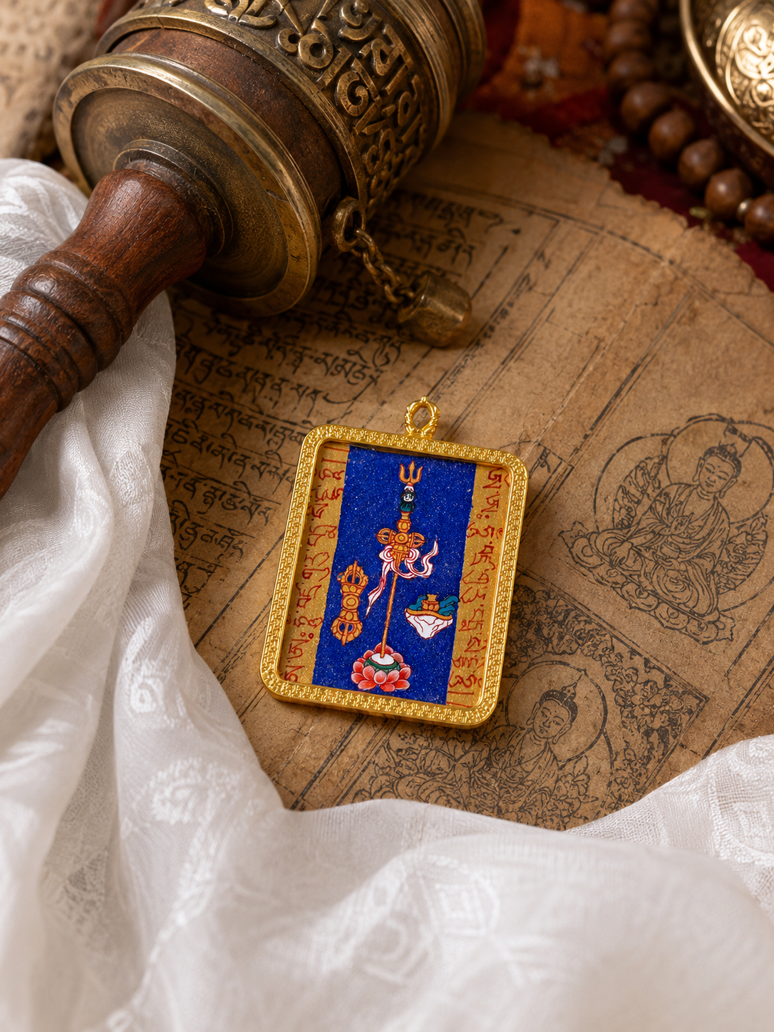 Padmasambhava Heart Mantra pendant laid on illustrated pages beside cream fabric