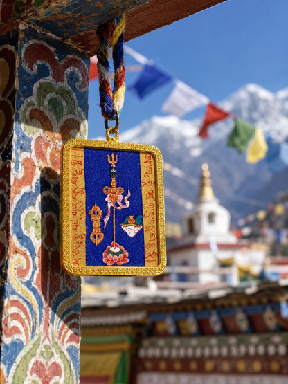 Blue Padmasambhava Heart Mantra pendant hanging beside a painted post with mountains behind