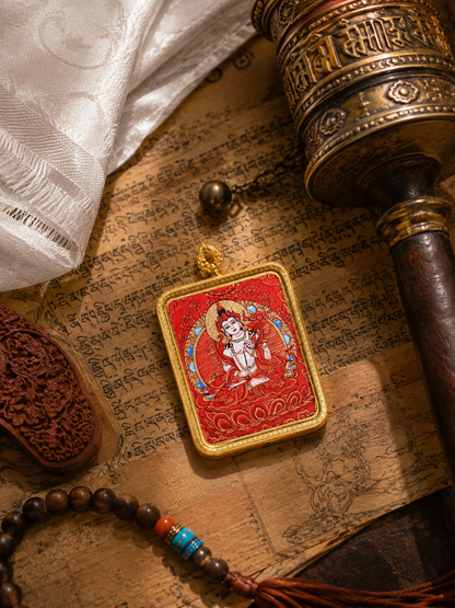 Mahasthamaprapta pendant laid on printed pages beside a strand of beads