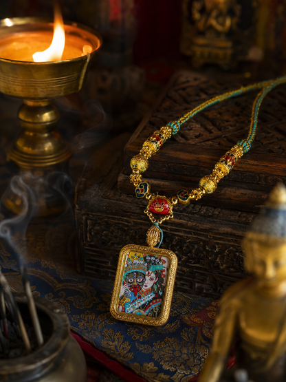 Zaki Lhamo pendant standing against a carved box, showing its colored painting and beaded necklace