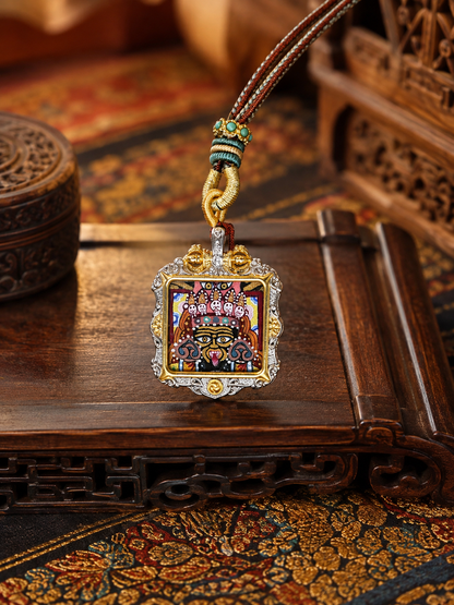 Square Zaki Lhamo ghau pendant with an ornate frame and decorative loop on a braided cord