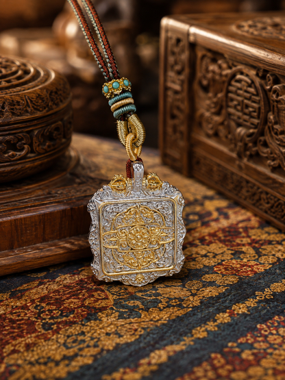 Reverse of the square ghau pendant, showing a circular gold-colored pattern within an ornate border