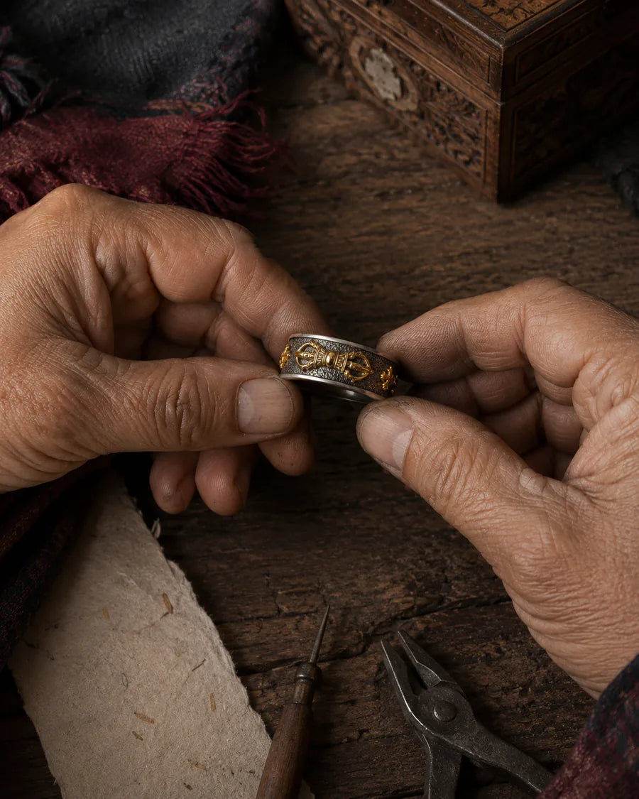 Hands examining the engraved surface of a two-tone ring